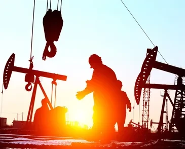 Oil field workers at sunset
